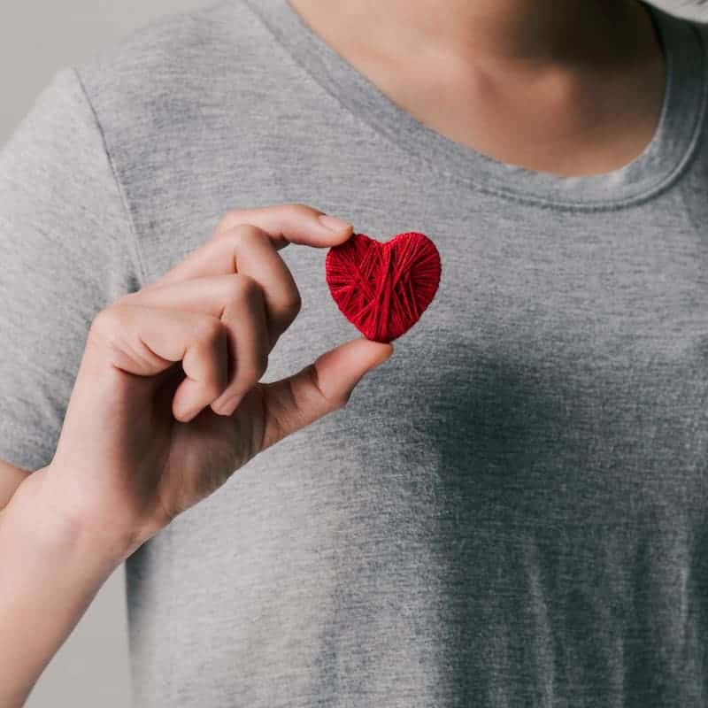 woman holding a red yarn heart